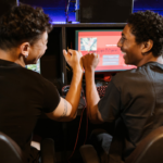 two males fist bumping in front of computers with games on them